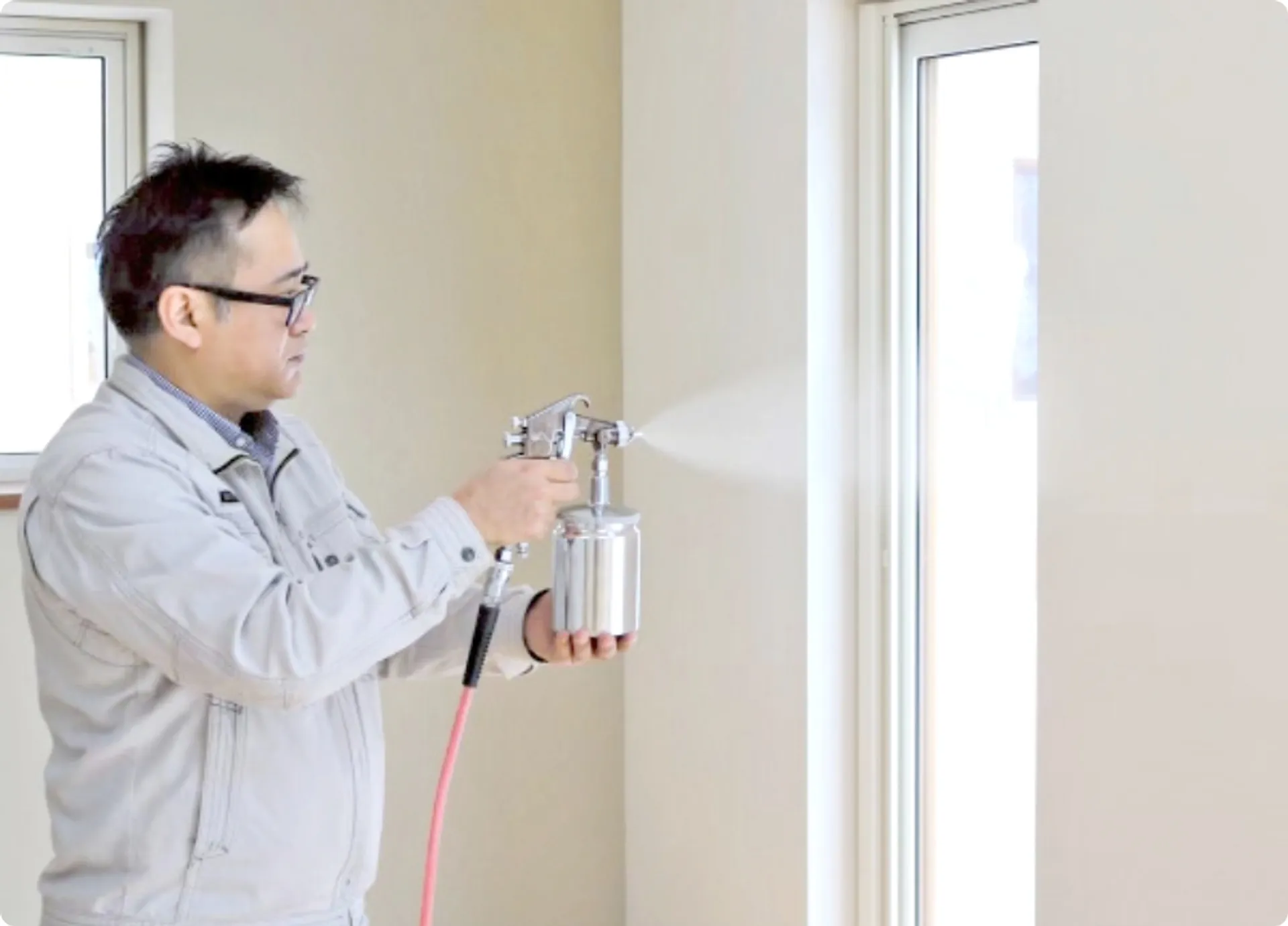 壁紙を剥がさずに室内の壁にAIリキッド仕上げを吹きつけ施工している職人の様子